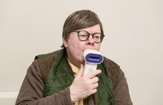 Person holding an N-Tidal handset to their mouth and breathing through it